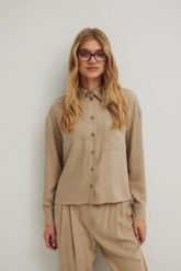 Koszula o prostym kroju z kieszonką w kolorze STONE BEIGE - ROMA-M/L. Brązowe koszule damskie Marsala, l, bez wzorów, z tkaniny, eleganckie, bez kołnierzyka, bez ramiączek. Za 359.90 zł.