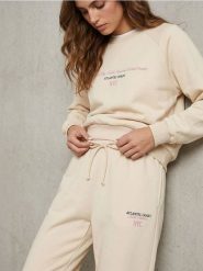 Spodnie regular jogger fleece z hafotwanym napisem NYC - kremowy. Białe spodnie sportowe damskie Sinsay, l, bez wzorów. Za 39.99 zł.