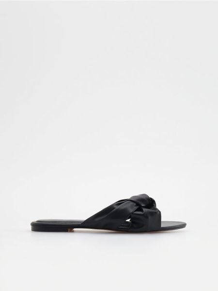 Klapki z imitacji skóry - czarny. Czarne klapki damskie Reserved, bez wzorów, ze skóry, bez obcasa, bez zapięcia. W wyprzedaży za 39.99 zł.