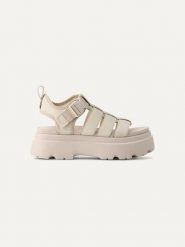 UGG Skórzane sandały "Cora" w kolorze kremowym rozmiar: 38. Brązowe sandały damskie Ugg, bez wzorów, z materiału, z otwartym noskiem, bez obcasa, na koturnie, bez zapięcia. Za 555.15 zł.