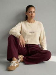 Bluza crewneck z haftowanym napisem NYC - kremowy. Białe bluzy damskie Sinsay, l, bez wzorów, bez kaptura. Za 39.99 zł.
