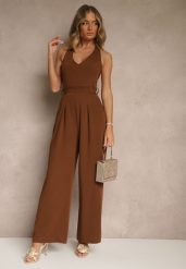 Brązowy Kombinezon o Taliowanym Kroju z Dekoltem Halter i Wiązanym Paskiem Malisena. Brązowe sukienki damskie Renee, bez wzorów, eleganckie, bez ramiączek. W wyprzedaży za 119.99 zł.
